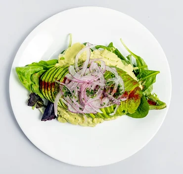Avocado Cream Salad: mixed greens with avocado slices and red onion on a white plate