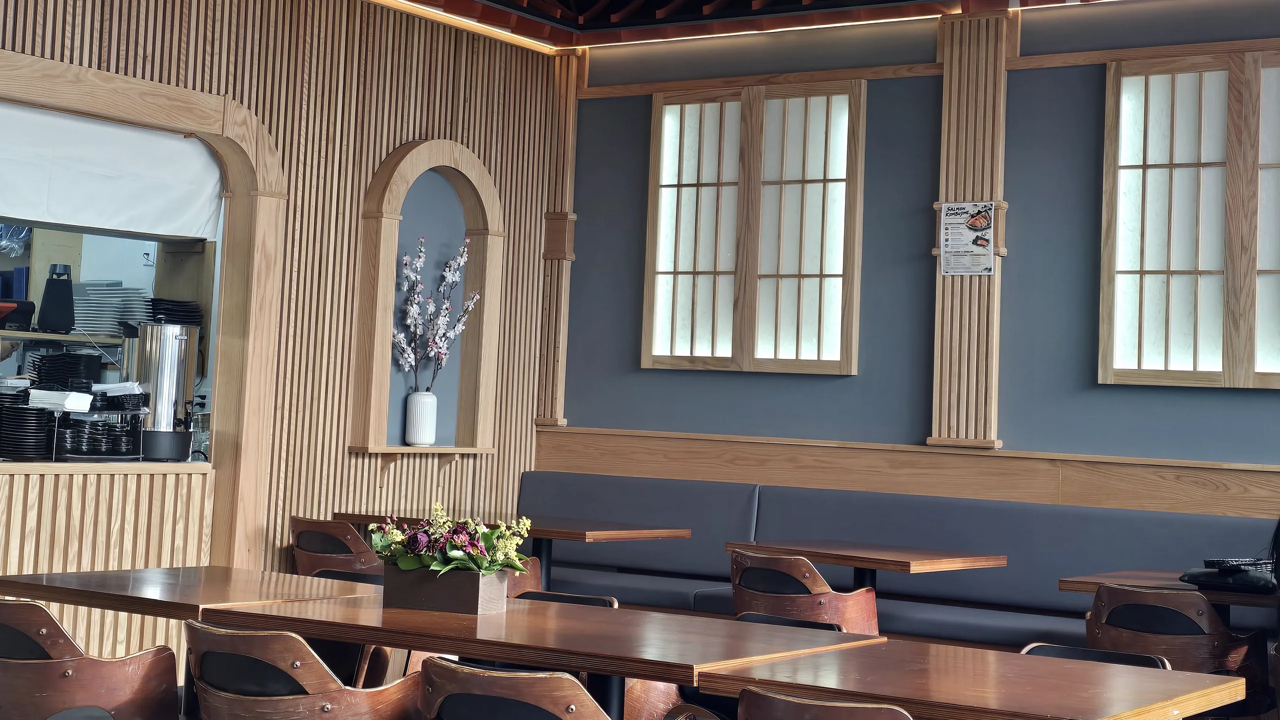 Rocky Maki dining room with wood-slat walls, shoji-style windows, pendant lights and wooden tables
