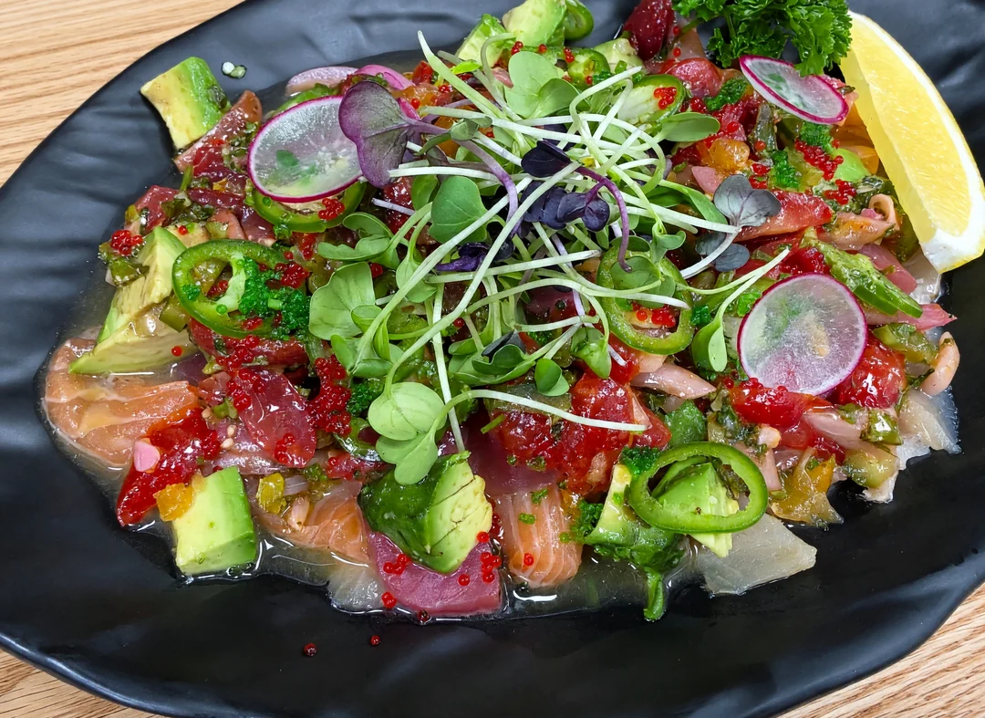 Rocky Maki Ceviche: salmon, tuna, avocado, jalapeño, radish and microgreens with tobiko on a black plate
